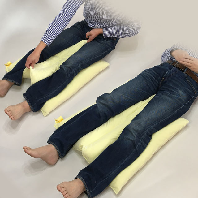 【使用例】下肢を乗せて股関節の内転予防に(下肢の交差予防に)。仙骨部・かかとの除圧に。両端溝に下肢を沿わせて乗せ、真ん中の溝の両端を指で引っ掛けて下肢の間から引き上げます。除圧マットレスに寝ても仙骨部とかかとに圧が集中する理由は、下肢の背部が浮いてすき間があるから。そこの隙間をクッションが埋めて体圧分散します。